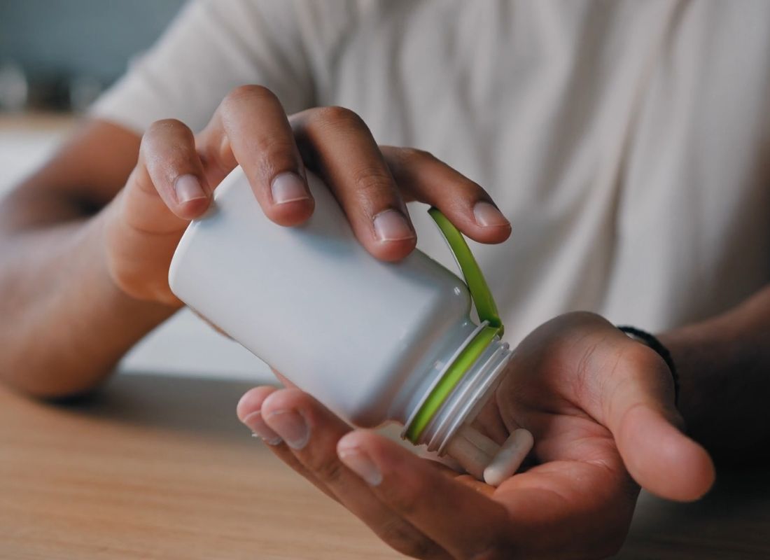 osoba uzima suplement vitamina d iz plastične bočice za lekove