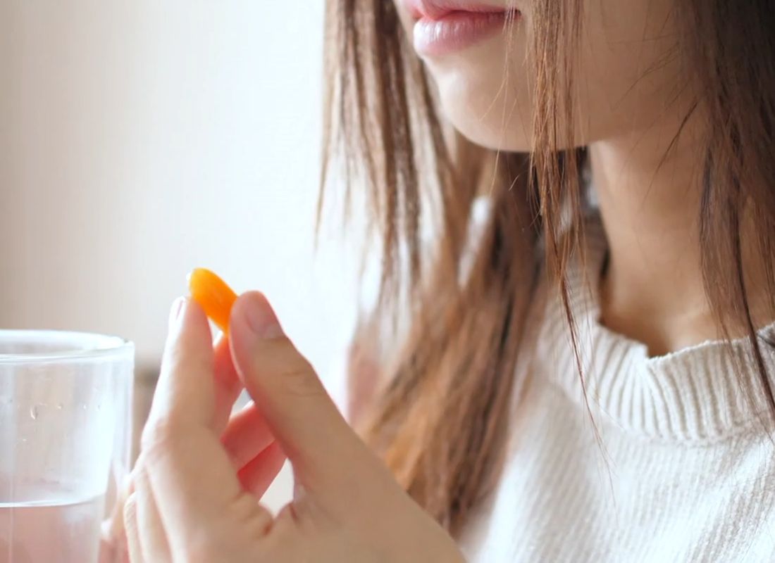 devojka drži suplement u ruci i čašu sa vodom