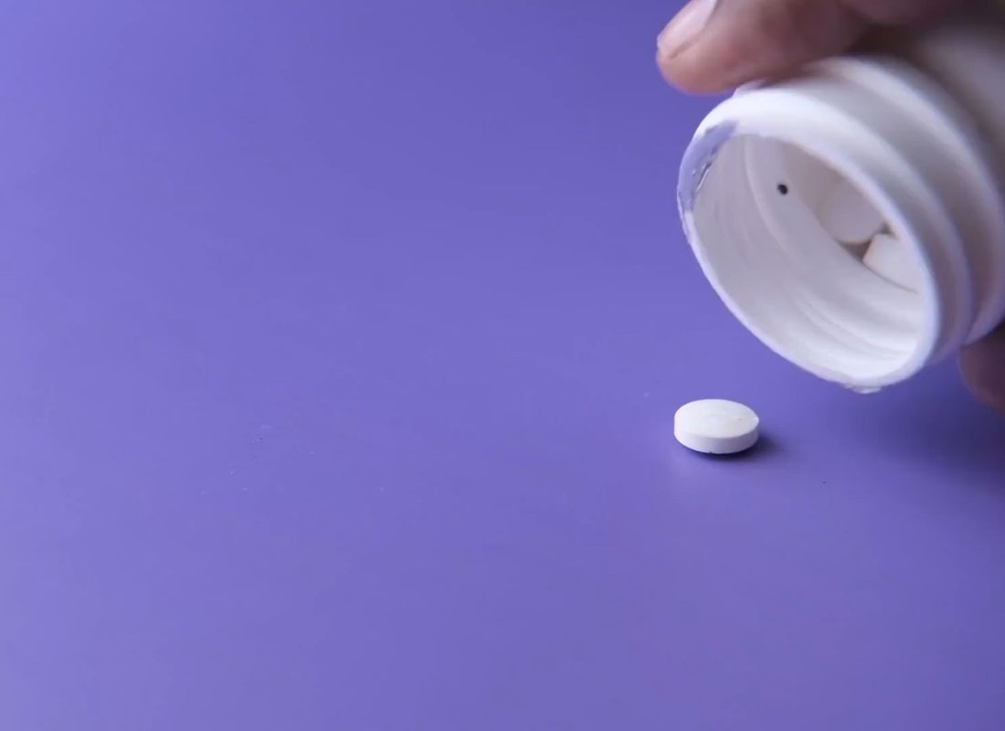 prikaz tablete i bočice za lekove na ljubičastoj pozadini